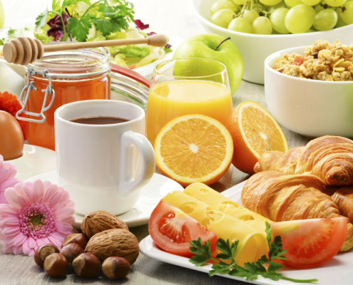 Breakfast consisting of fruits, orange juice, coffee, honey, bread and egg. Balanced diet